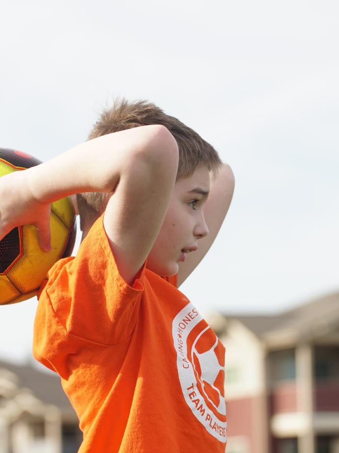 Youth soccer participant winding up to throw the ball back in bounds at the YMCA
