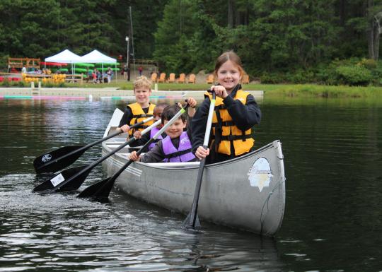 Four children canoeing at Camp Lake Helena