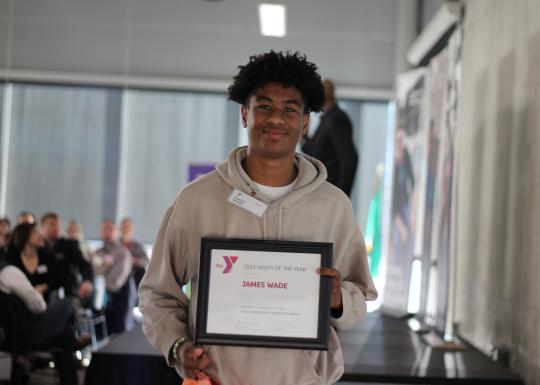 YMCA 2023 Youth of the Year student, James Wade smiling with his award certificate.