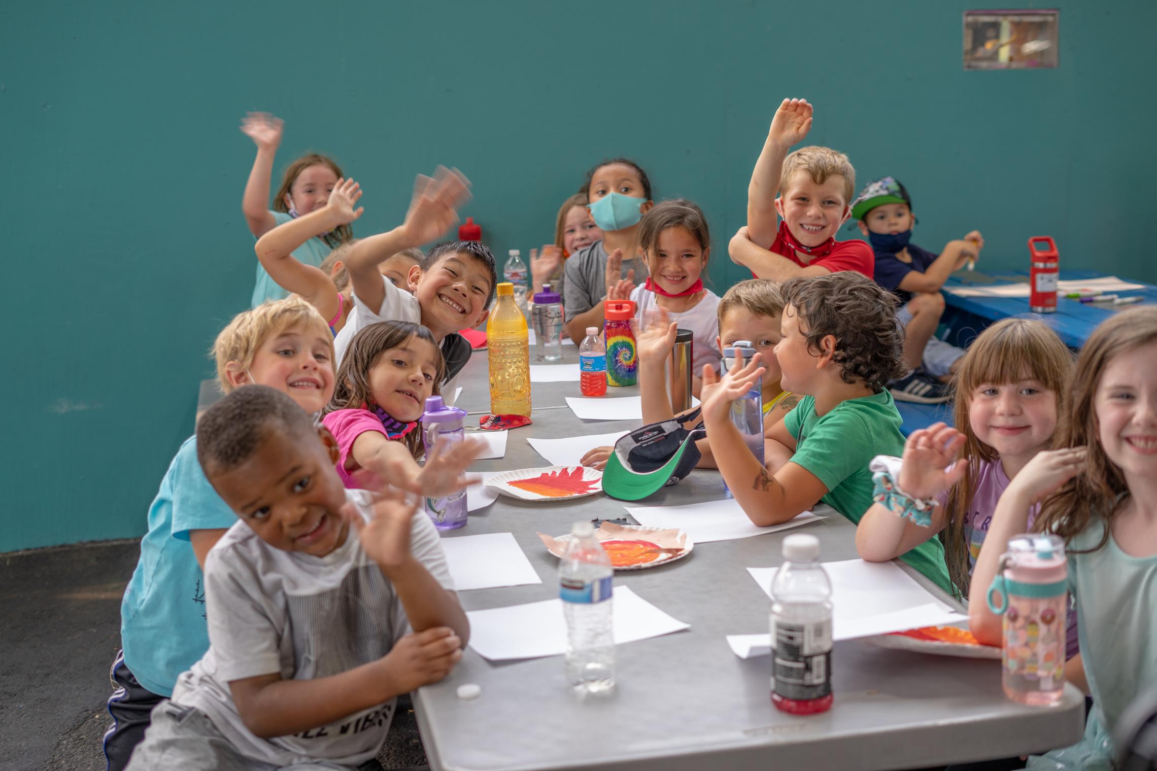 Youth wave while doing crafts at ELC