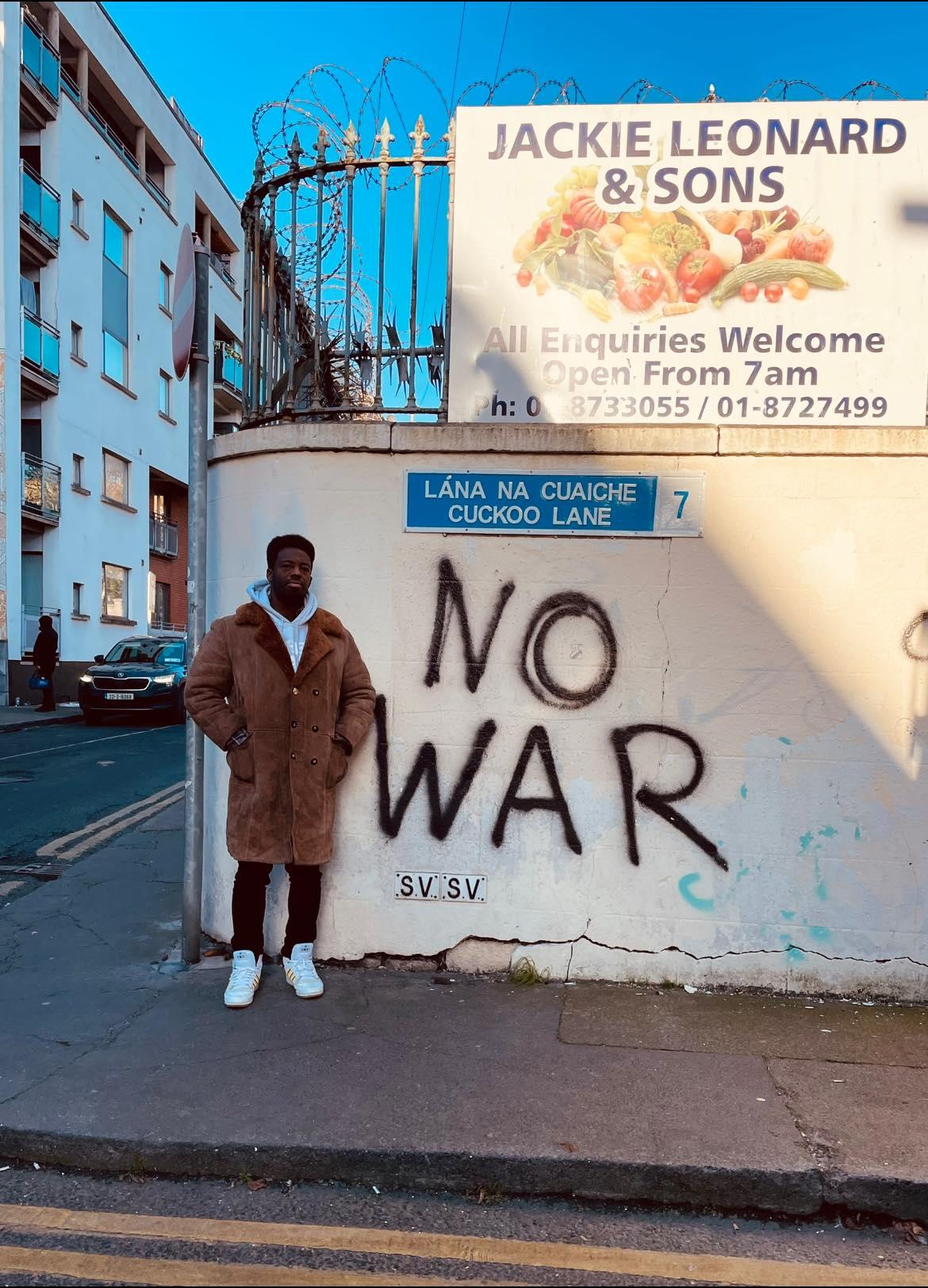 Kwabi Amoah-Forson poses in front of the words NO WAR in Dublin, Ireland 