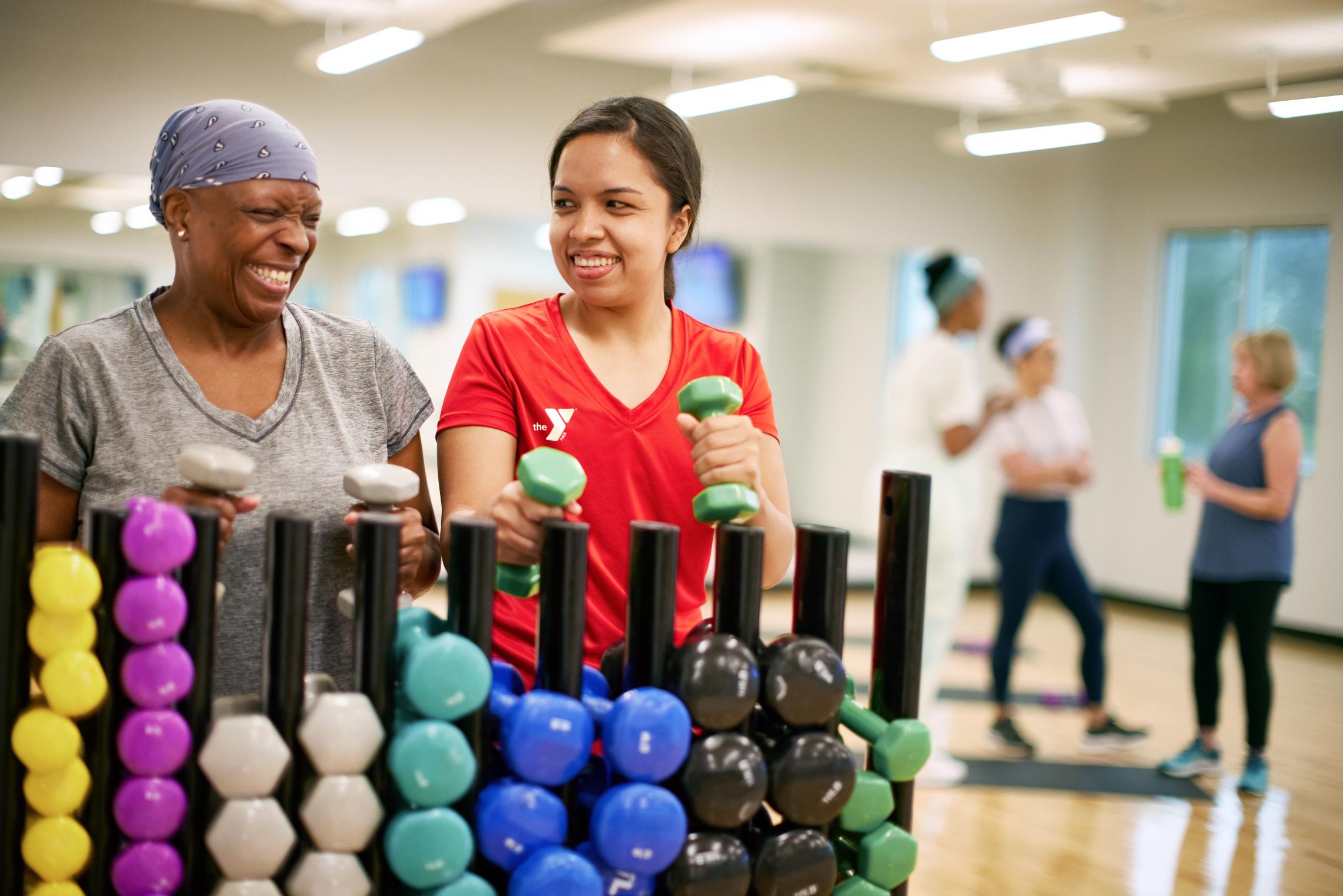 Group exercise participant selects dumbbells for a workout at the YMCA