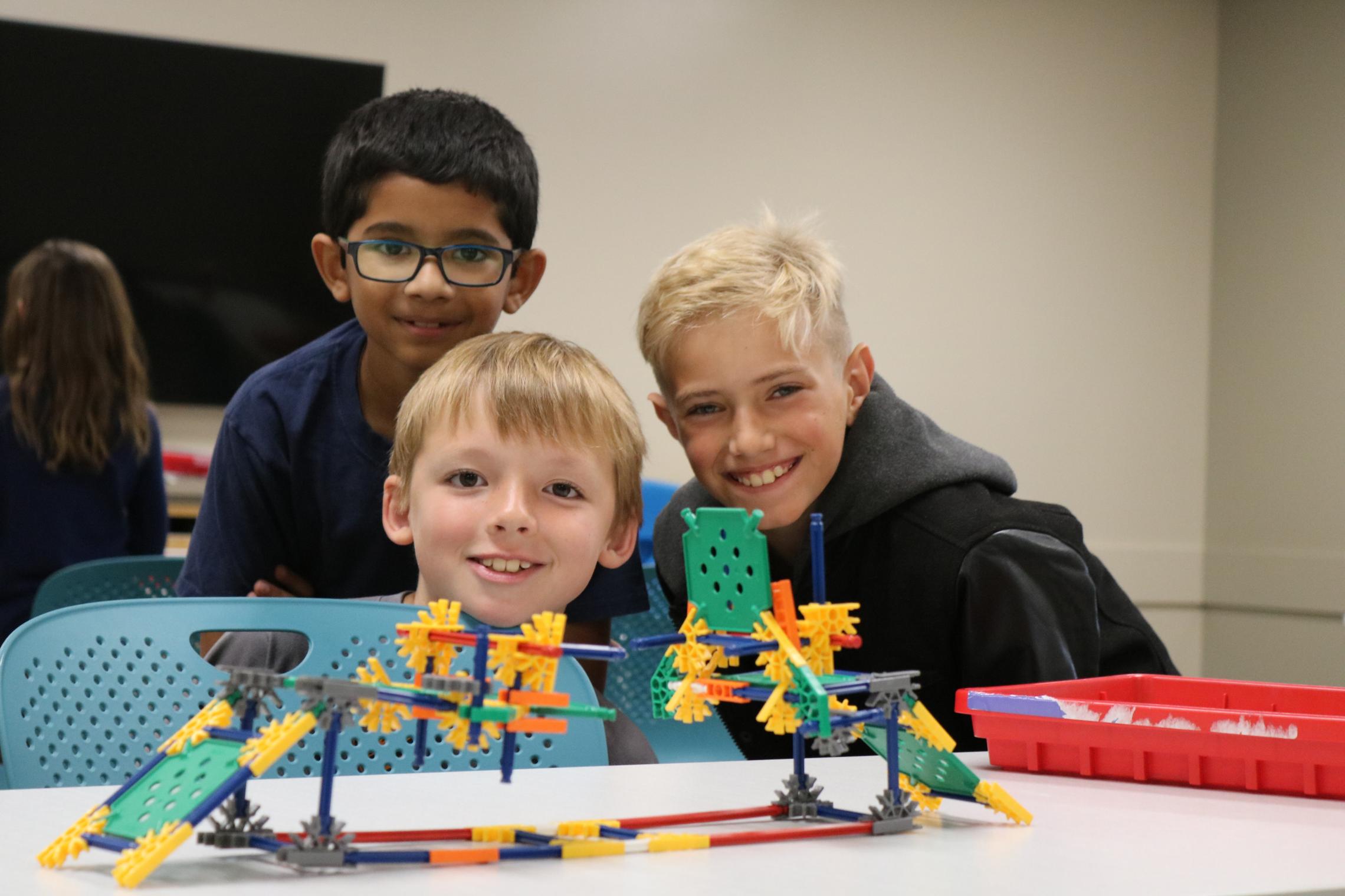 Summer camp participants pose behind a Kinex building block creation at the YMCA