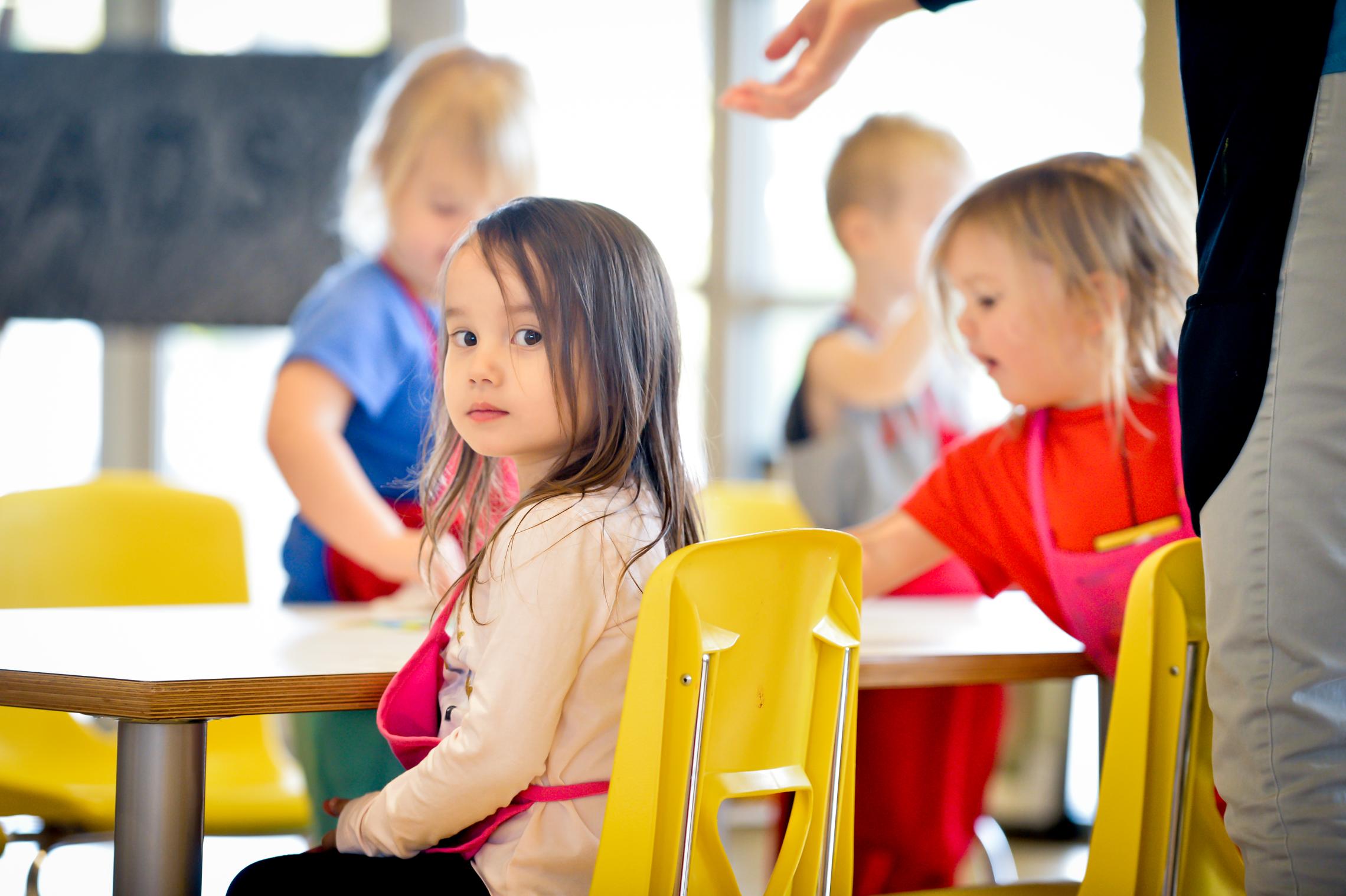 Gordon Family YMCA arts program toddler looks inquisitively at the camera during a painting session at the YMCA