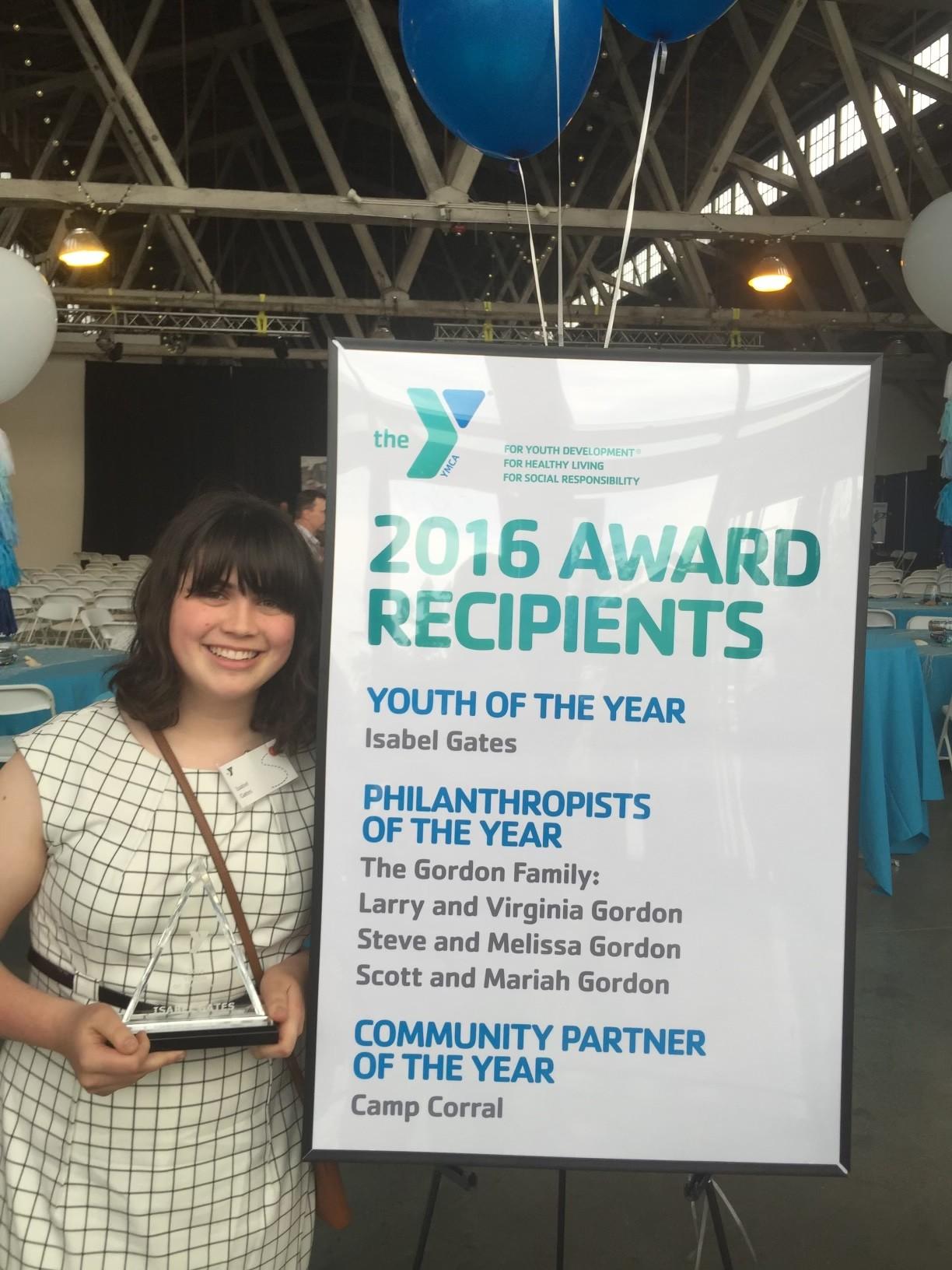 Photo of Isabel Gates next to a sign of the 2016 YMCA award recipients