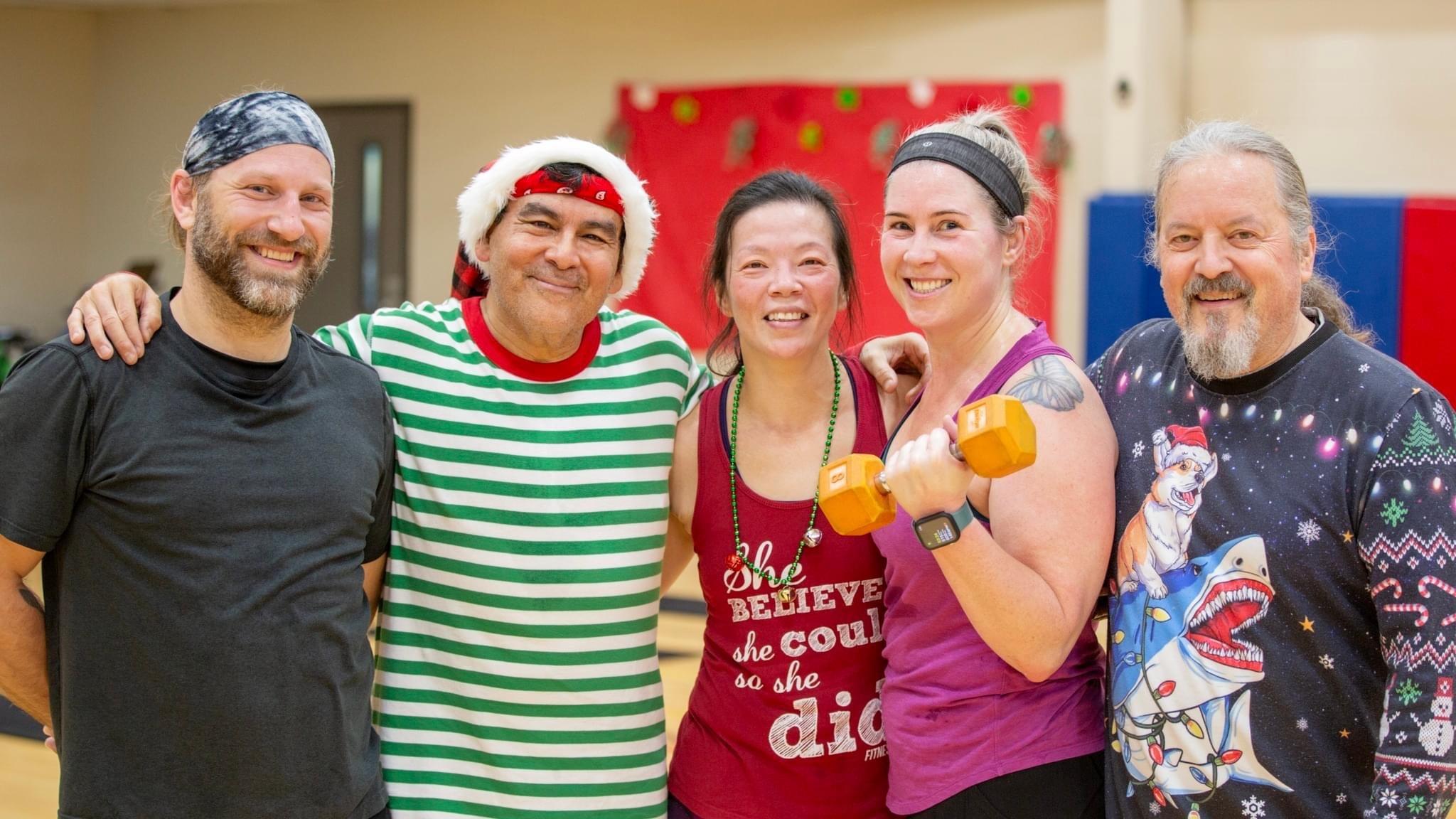 12 Days of FITmas participants pose in Holiday apparel and pose after a holiday themed circuit workout at the YMCA.