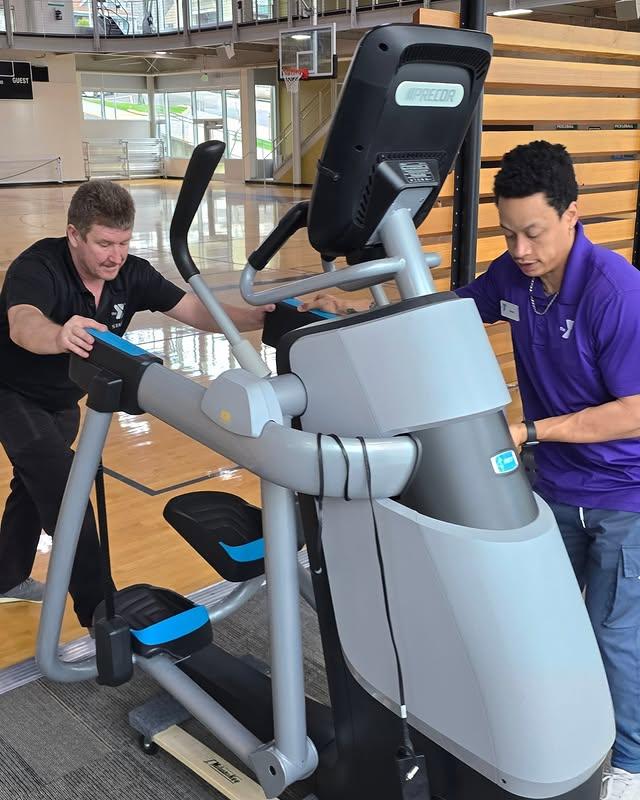 Two people move workout equipment at the YMCA