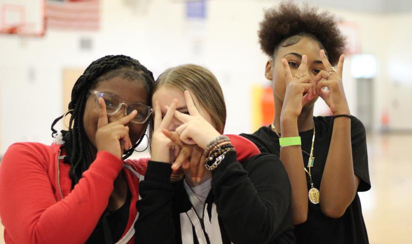 A group of friends flash peace signs while hanging out at Teen Late Nite at the YMCA