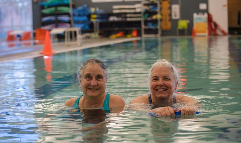 Two people smile in the pool at the YMCA