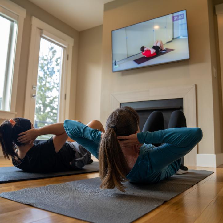 Mother and daughter doing sit ups together at home