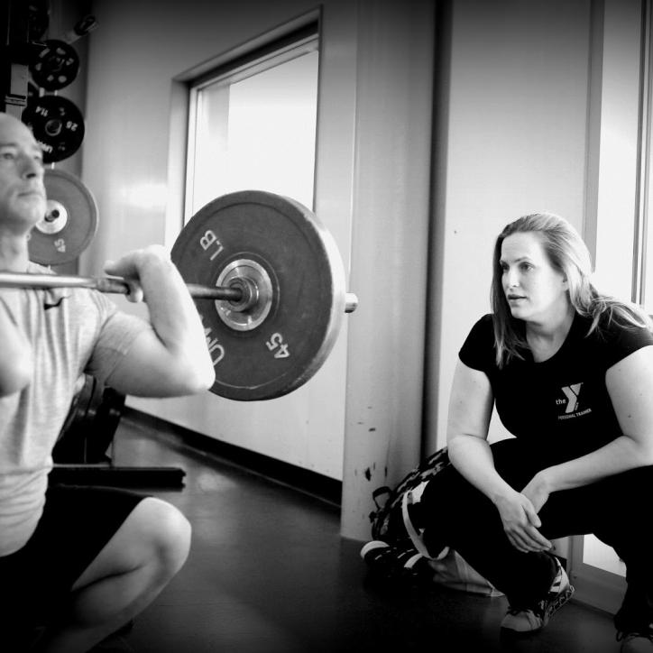 Personal trainer providing proper squat form coaching