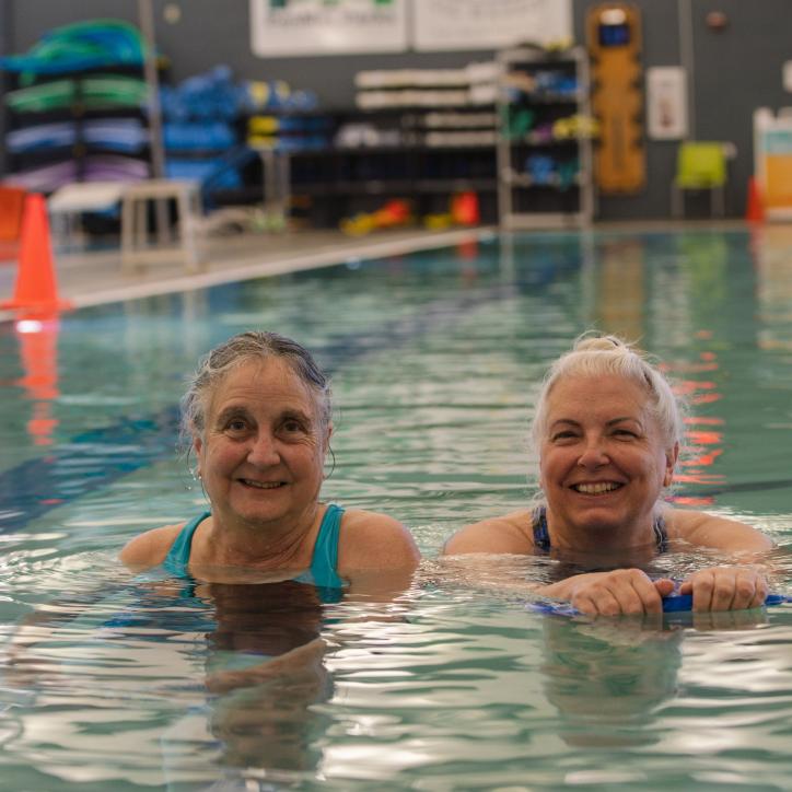 Two people smile in the pool at the YMCA
