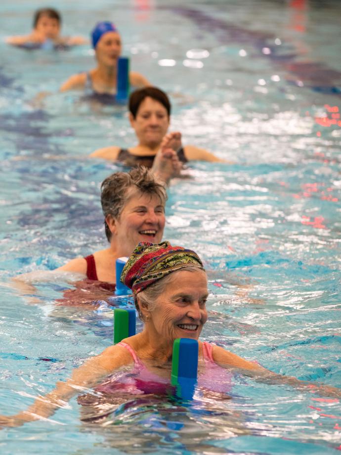 Aqua boot camp participants line up in the pool using pool noodles