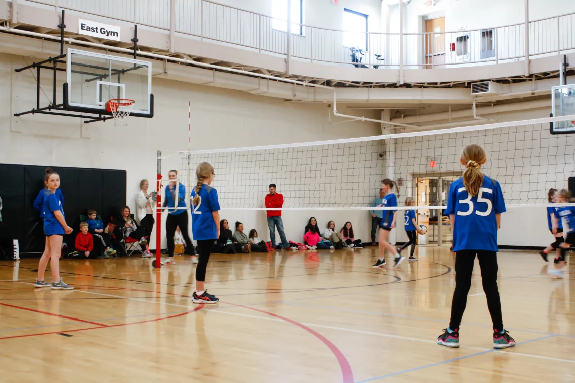 Volleyball players wait for the next serve during a game at the YMCA