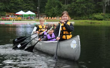 Four children canoeing at Camp Lake Helena