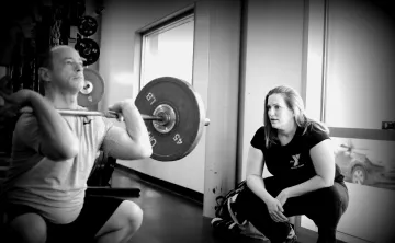 Personal trainer providing proper squat form coaching