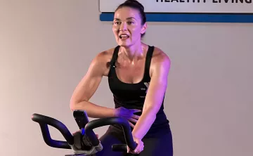 Instructor Jen Garrison sweats and speaks between sprints on a stationary cycling class on YMCA360