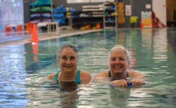 Two people smile in the pool at the YMCA